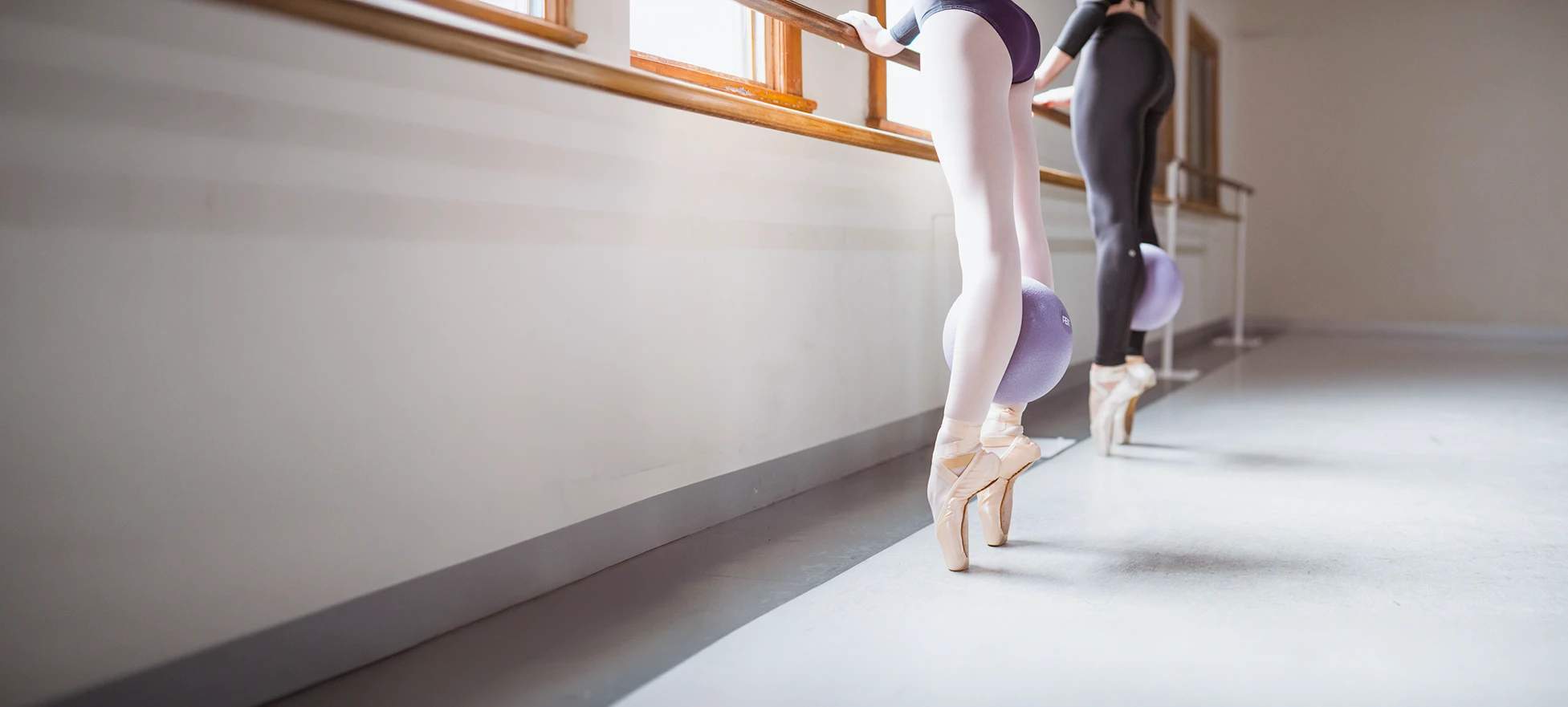 Dancers on pointe at the barre with exercise balls